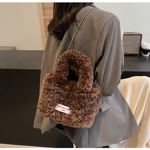 Detail of plush faux fur shoulder bag in dark brown with metal ball chain strap