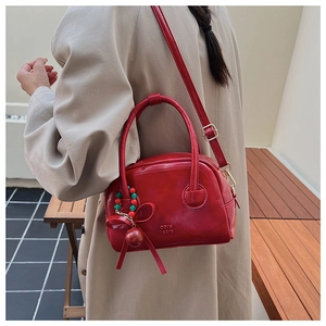 Détail du sac oreiller rouge avec marquage COIH 2DN et breloque noeud en perles