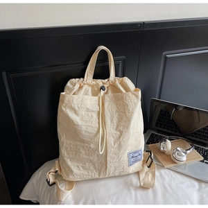 Detail of light beige drawstring backpack with brand label and water-resistant fabric