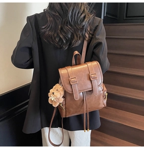 Detailansicht eines braunen Vintage-Lederrucksacks mit Bärenanhänger an Treppen