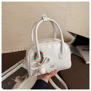 Détail du sac oreiller crème avec nœud 3D et breloques dans un décor décontracté