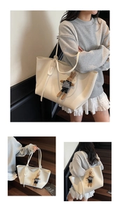 Detailed view of spacious white leather tote bag featuring a cute rabbit charm accessory