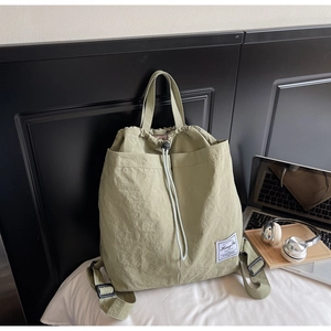 Close-up of grass green drawstring backpack with dual front pockets and nylon texture