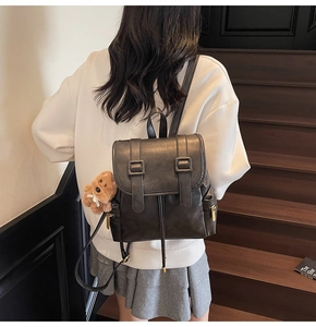 Detailansicht eines schwarzen Vintage-Rucksacks mit goldenen Reißverschlüssen und Bär