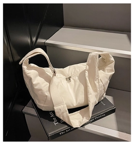 Minimalist white nylon crescent bag with wide shoulder strap and silver zipper closure