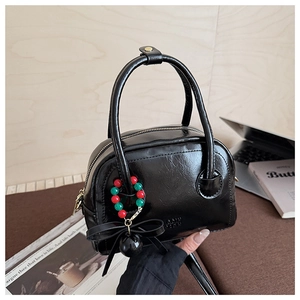 Détail du sac oreiller en cuir PU noir brillant avec un charmant nœud et des perles
