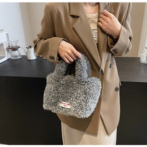 Detail view of plush grey fleece bag featuring a metal chain strap and woven label