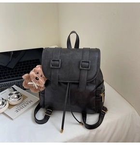 Detailansicht eines schwarzen Vintage-Rucksacks aus PU-Leder mit Schnallen und Bärenanhänger