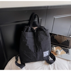 Close-up of black drawstring backpack made of water-resistant nylon with logo label