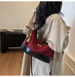 Detail of vintage quilted burgundy suede shoulder bag with gold twist lock and bead tassel