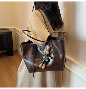 Detail of vintage brown leather tote bag with a cute rabbit plush charm for daily commuting