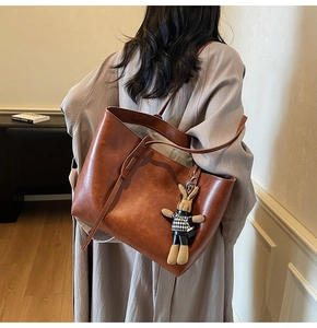 Detail of caramel brown tote bag with leather texture and cute rabbit plush charm