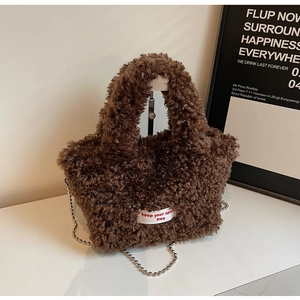 Detailed macro of dark brown plush handbag with silver bead chain strap and embroidered label