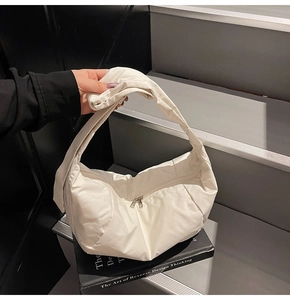Close-up of white padded nylon dumpling bag featuring silver zipper and wide strap