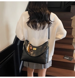 Detail of black quilted shoulder bag featuring gold twist lock and beaded tassel