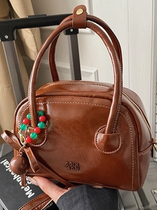 Sac à main marron en similicuir avec surpiqûres blanches et pendentif perlé