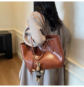 Close-up of caramel brown tote bag featuring a decorative houndstooth rabbit pendant