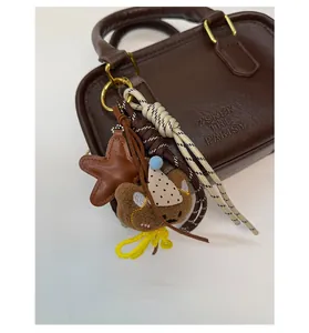 Close-up of brown plush bear pendant and star charm on leather handbag detail