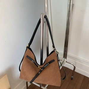 Detailed close-up of brown suede hobo bag with black leather straps and gold metal buckles