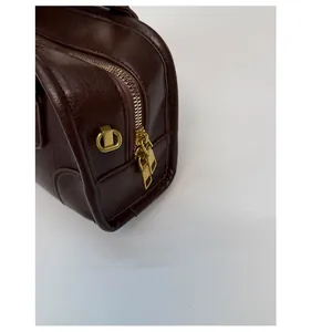 Detail of dark brown leather bag showing smooth dual golden metal zippers and D-rings