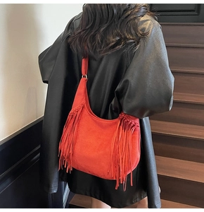 Gros plan d'un sac à bandoulière rouge vif à franges avec une veste en cuir noir