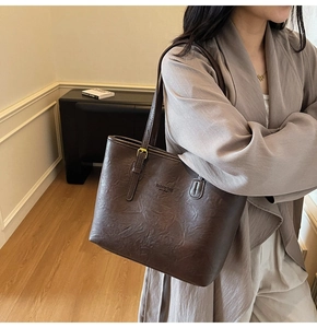 Close-up of a vintage brown leather tote bag with embossed fashion text and gold buckle