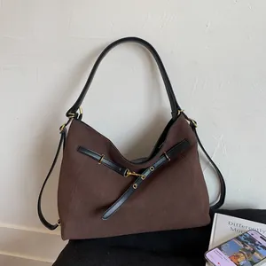 Detail view of brown canvas hobo bag with black leather straps and gold metal buckle