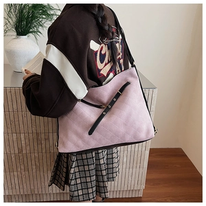 Detail view of pink quilted tote bag with black leather straps and golden hardware