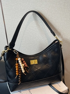 Vintage black quilted hobo bag with a gold lock and ethnic style beaded charm decoration