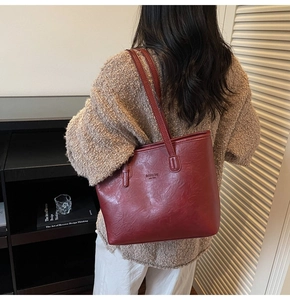 Detailed view of the dark red tote bag on a model wearing a warm beige knitted sweater