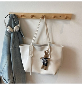 Detail of cream leather tote bag with cute rabbit charm hanging on wooden hook