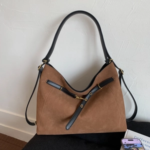 Detailed close-up of brown suede tote bag with black leather straps and gold hardware