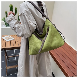 Detail of bright green tote bag with diamond stitching and brown leather straps