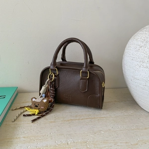Close-up of vintage dark brown faux leather handbag with fine texture and cute bear charm