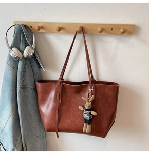 Brown vintage tote bag detail with houndstooth bunny charm and textured faux leather surface