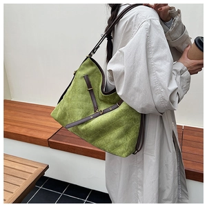 Detail of moss green quilted suede tote bag featuring brown leather straps and gold buckles