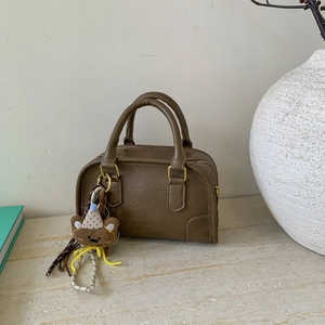 Close-up of olive green vintage Boston bag with a cute bear charm and golden hardware