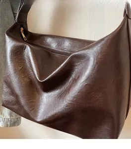 Detail of soft dark chocolate PU leather texture and metal zipper on hobo bag