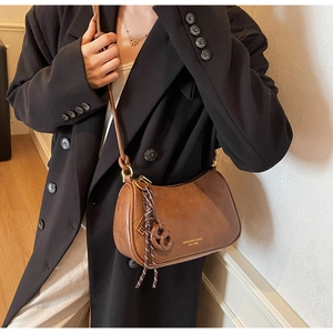 Detail view of brown vintage leather hobo bag with gold logo and elegant tassel