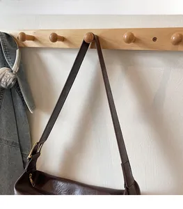 Detail of a deep brown hobo bag with a shiny leather texture and adjustable metal buckle strap