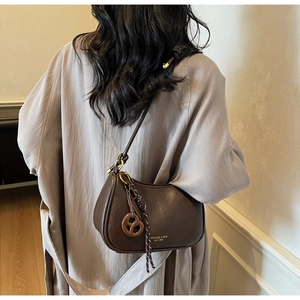 Detail of dark brown leather crescent bag with retro gold ring and knot charm detail