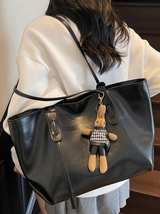 Chic black faux leather tote bag with rabbit charm shown on a model on wooden stairs