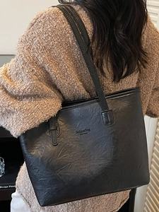 Stylish black PU leather tote bag for women with fashion bag text on shoulder of a model