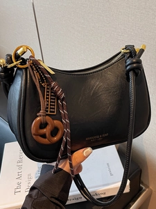 Retro black faux leather hobo bag with gold logo and unique charms on a shoulder strap