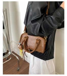 Detailed view of brown leather bag with brand embossing and cute hanging accessories