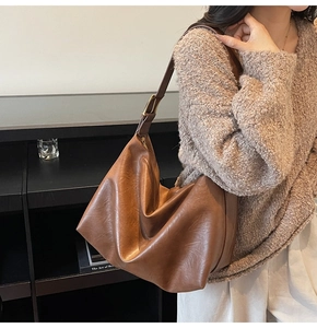Detail of caramel brown leather tote bag with vintage texture and metallic buckle