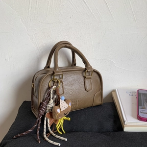 Detail view of brown vintage PU leather handbag with teddy bear charm and woven cord