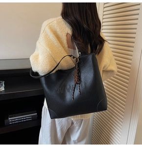 Detail of woven texture black tote bag with embossed letters and long shoulder straps