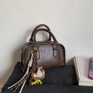 Detailed close-up of dark brown vintage handbag with gold hardware and bear charm