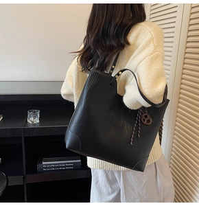 Detail of woven texture black tote bag with VWT logo and brown bow charm detail